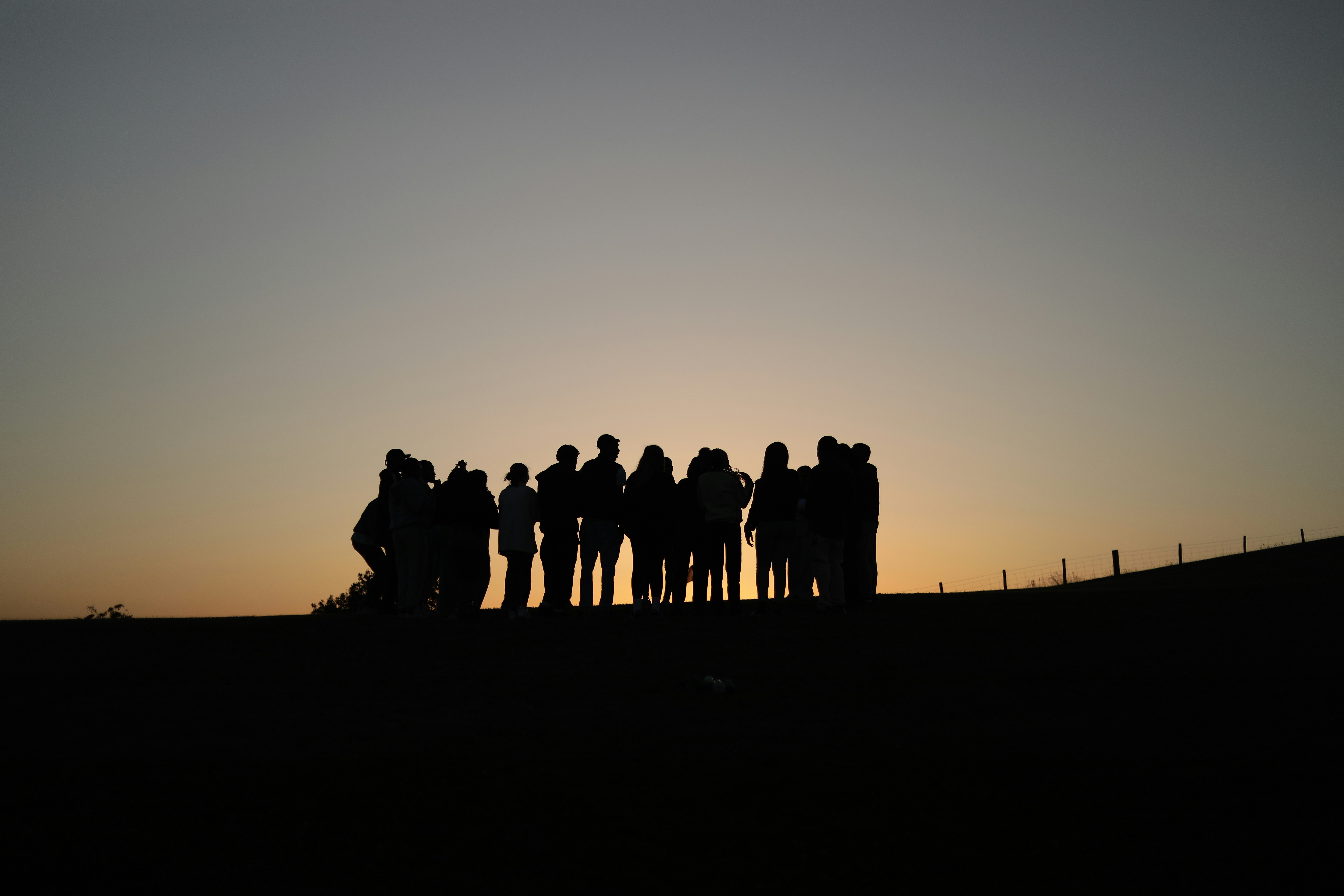 A group gathered together, silhouetted against a sunset sky